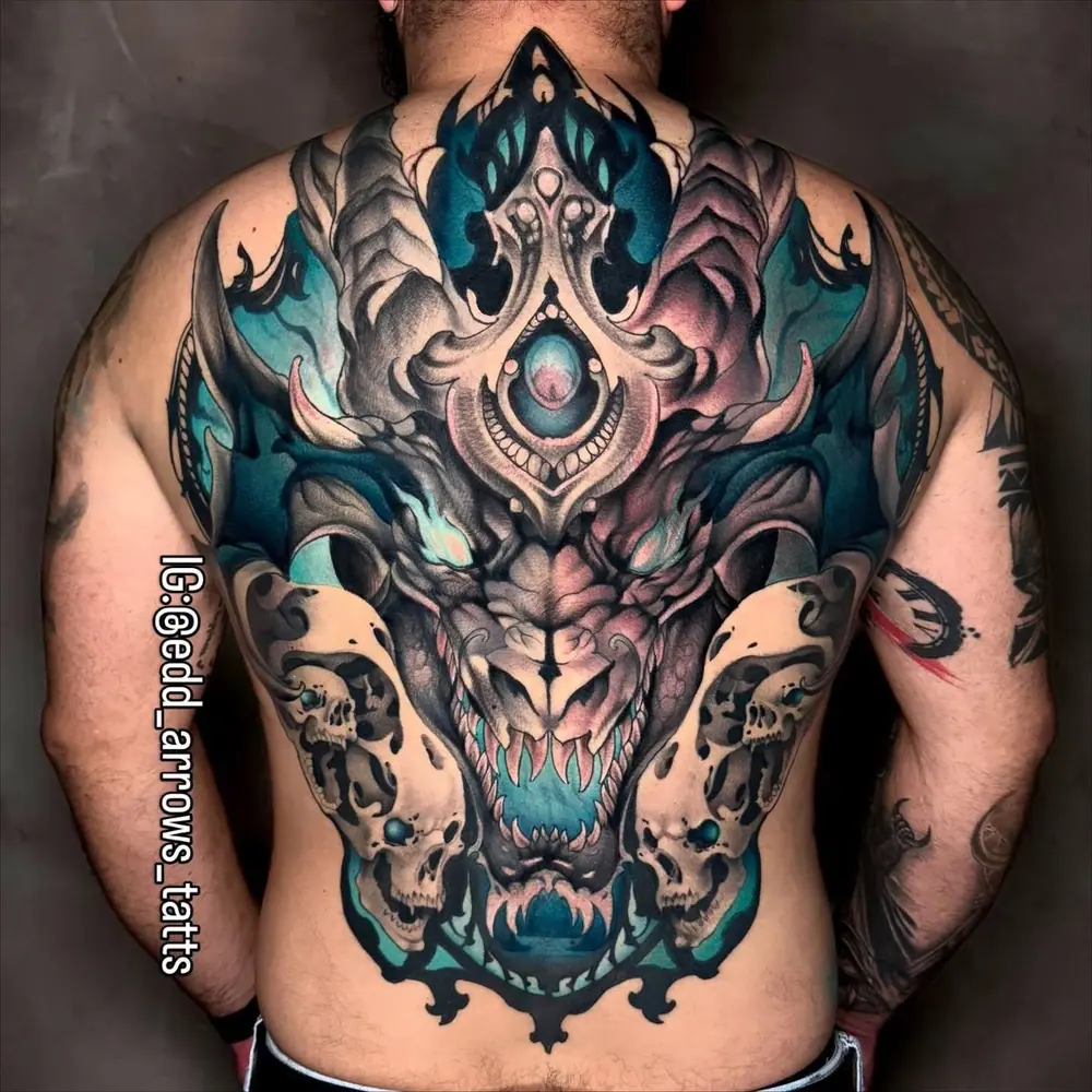 Espalda completa con un dragón con cuernos y detalles turquesa entre dos cráneos, neotradicional a color