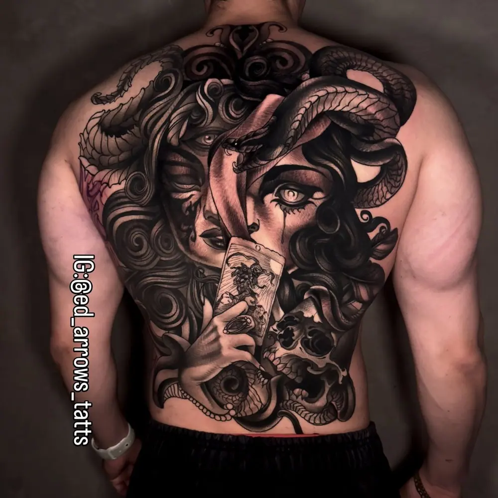 Espalda completa en black and grey: una bruja con serpientes en el cabello sostiene una carta del tarot