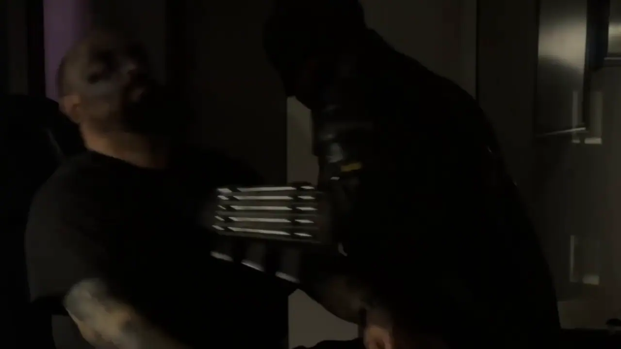 Escena del video: el justiciero de traje negro frente a un cliente en el estudio